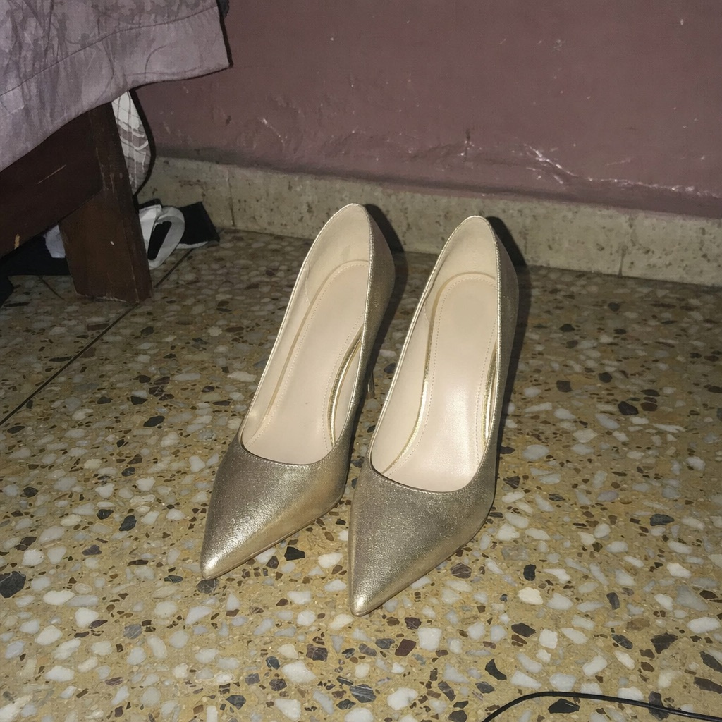 A seller’s phone photo of gold heels on a tiled floor